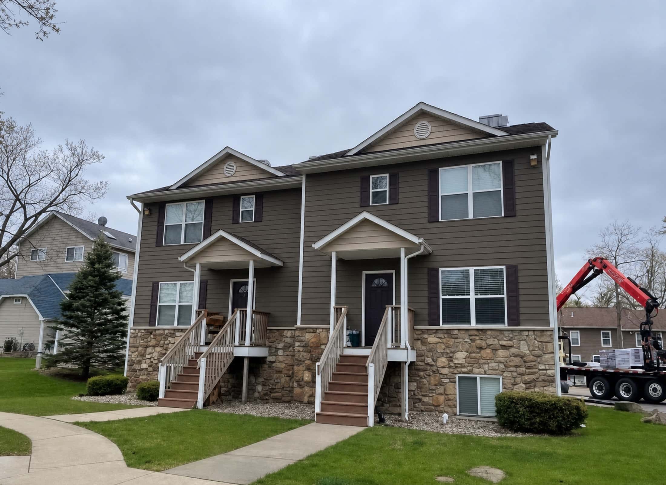 Finished duplex exterior with new siding, stone accents, and roof