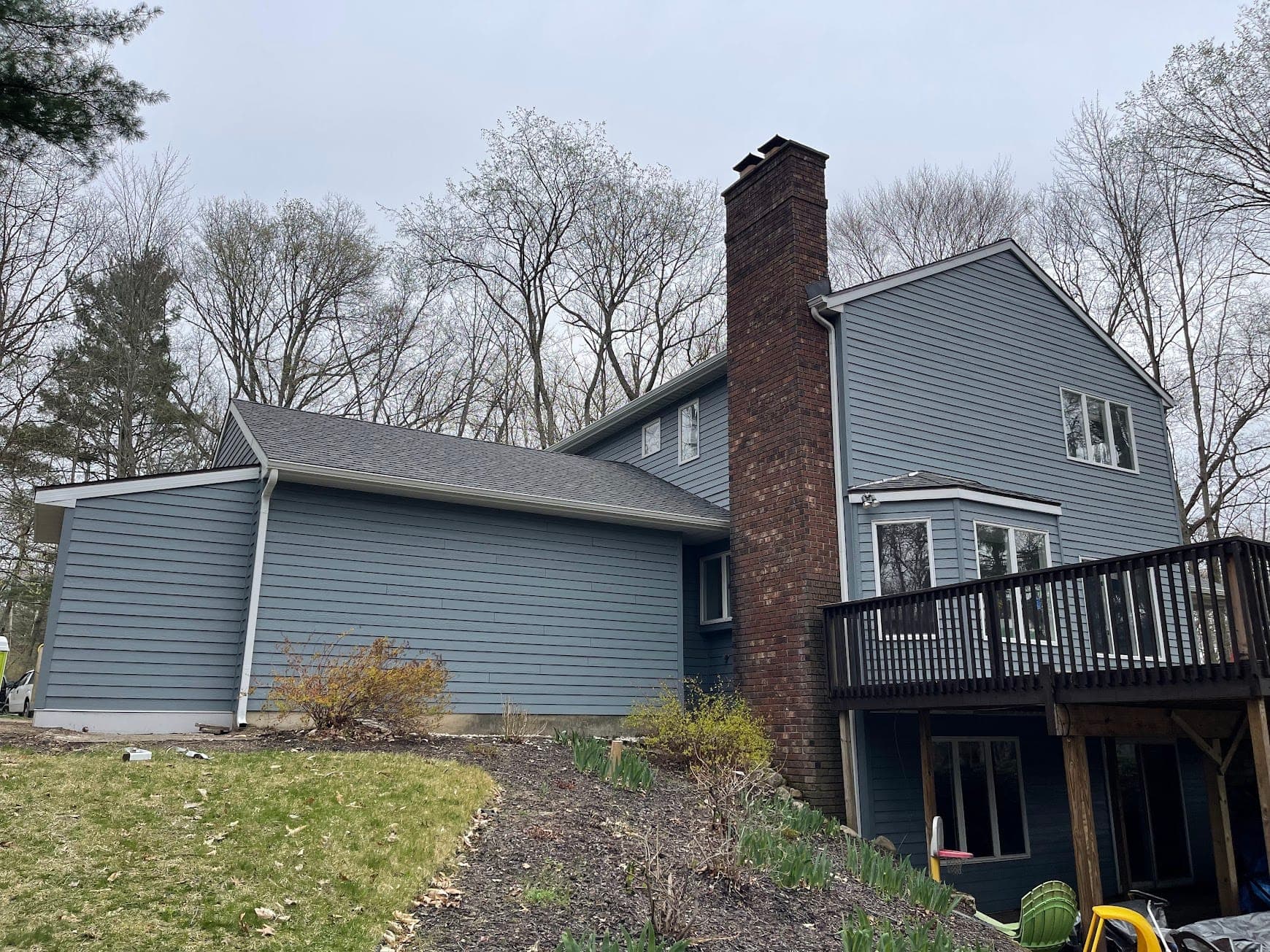 Finished blue-gray home exterior with a new roof and brick chimney in West Michigan