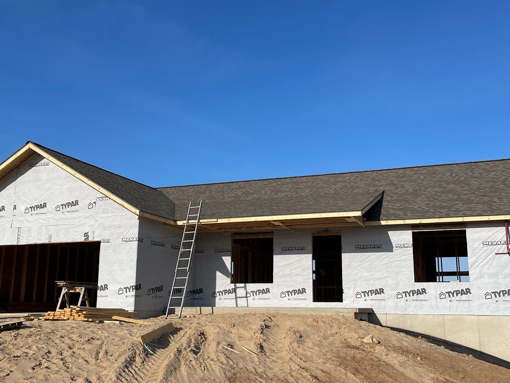 A West Michigan build with its finished shingle roof under a clear blue sky