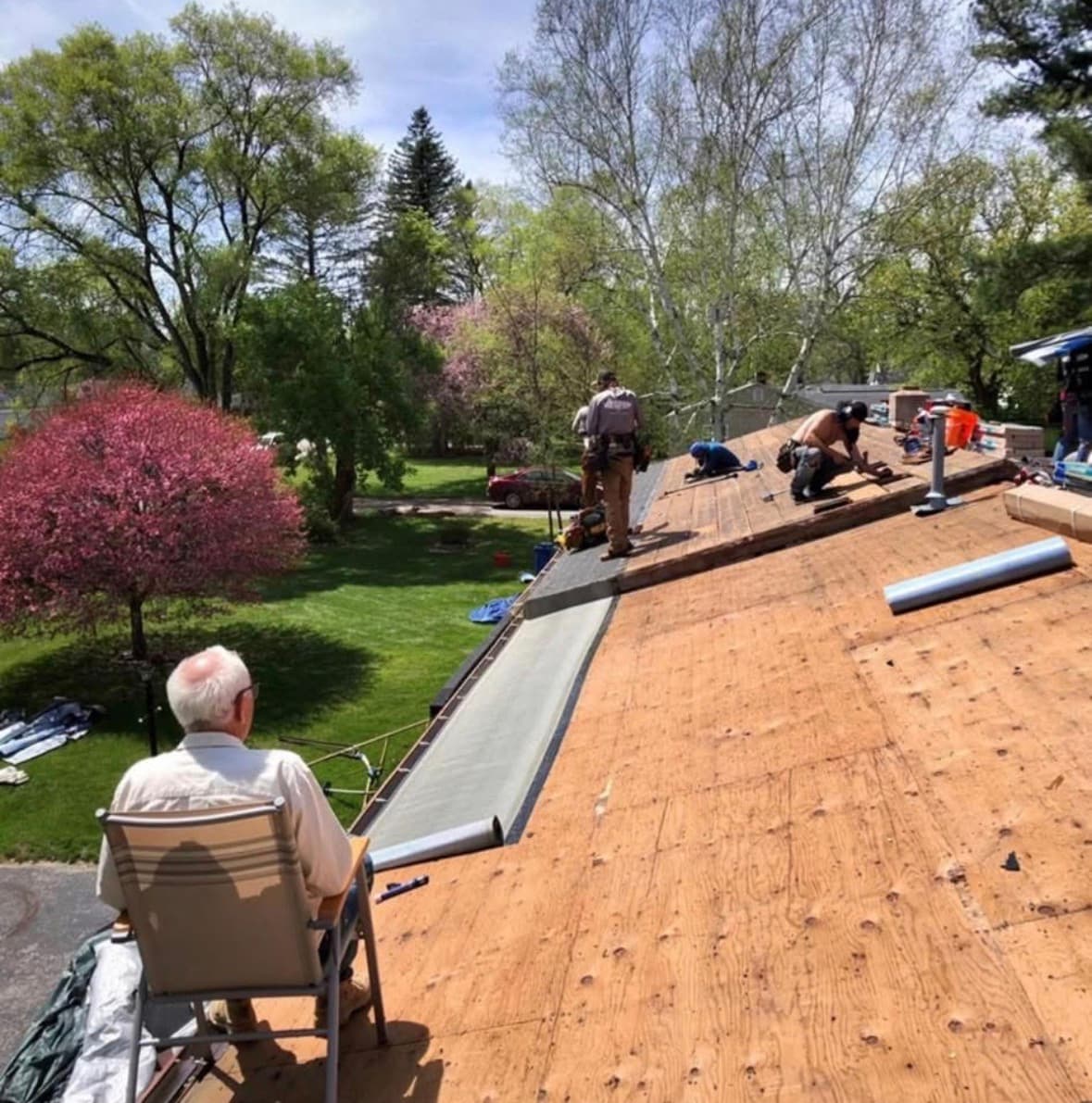A Grand Rapids homeowner watching the Essential Exteriors crew replace their roof