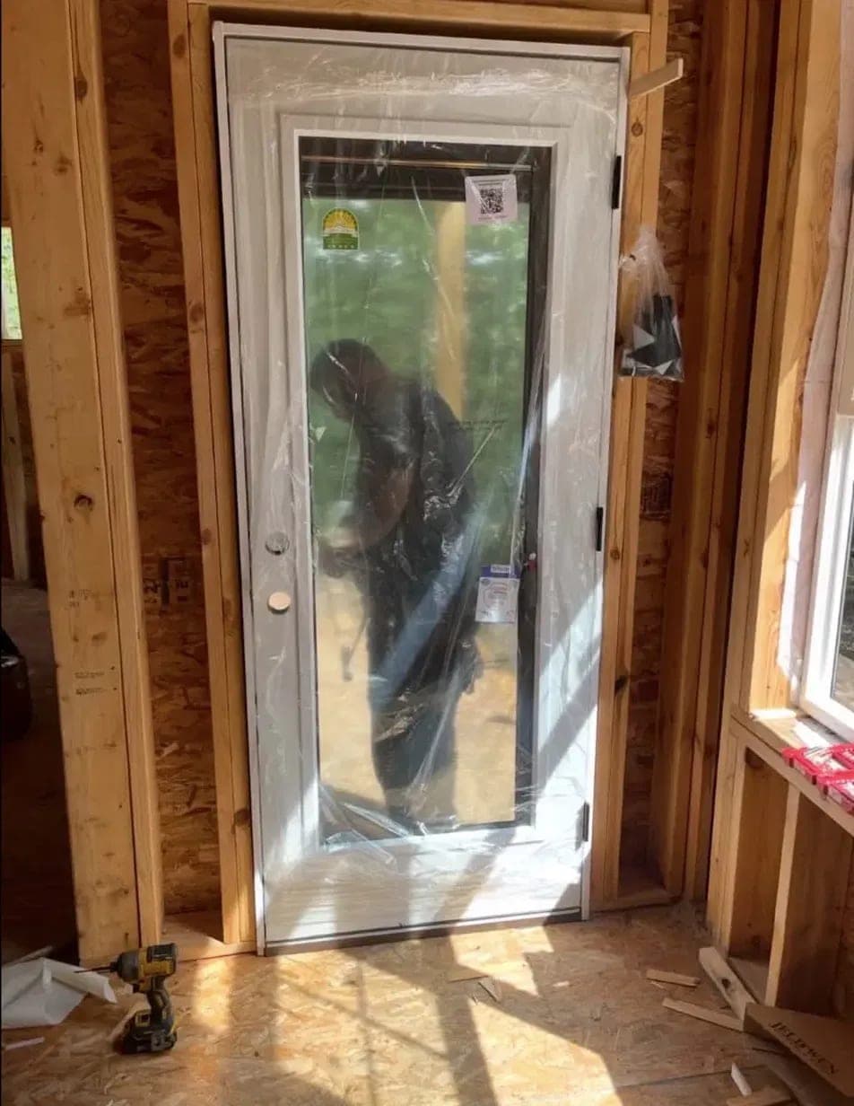 A full-glass white steel entry door installed in a framed opening