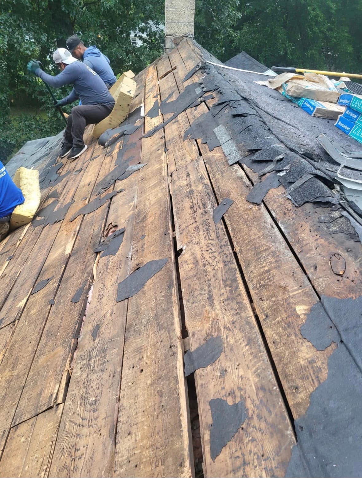Crew stripping old shingles to plank decking