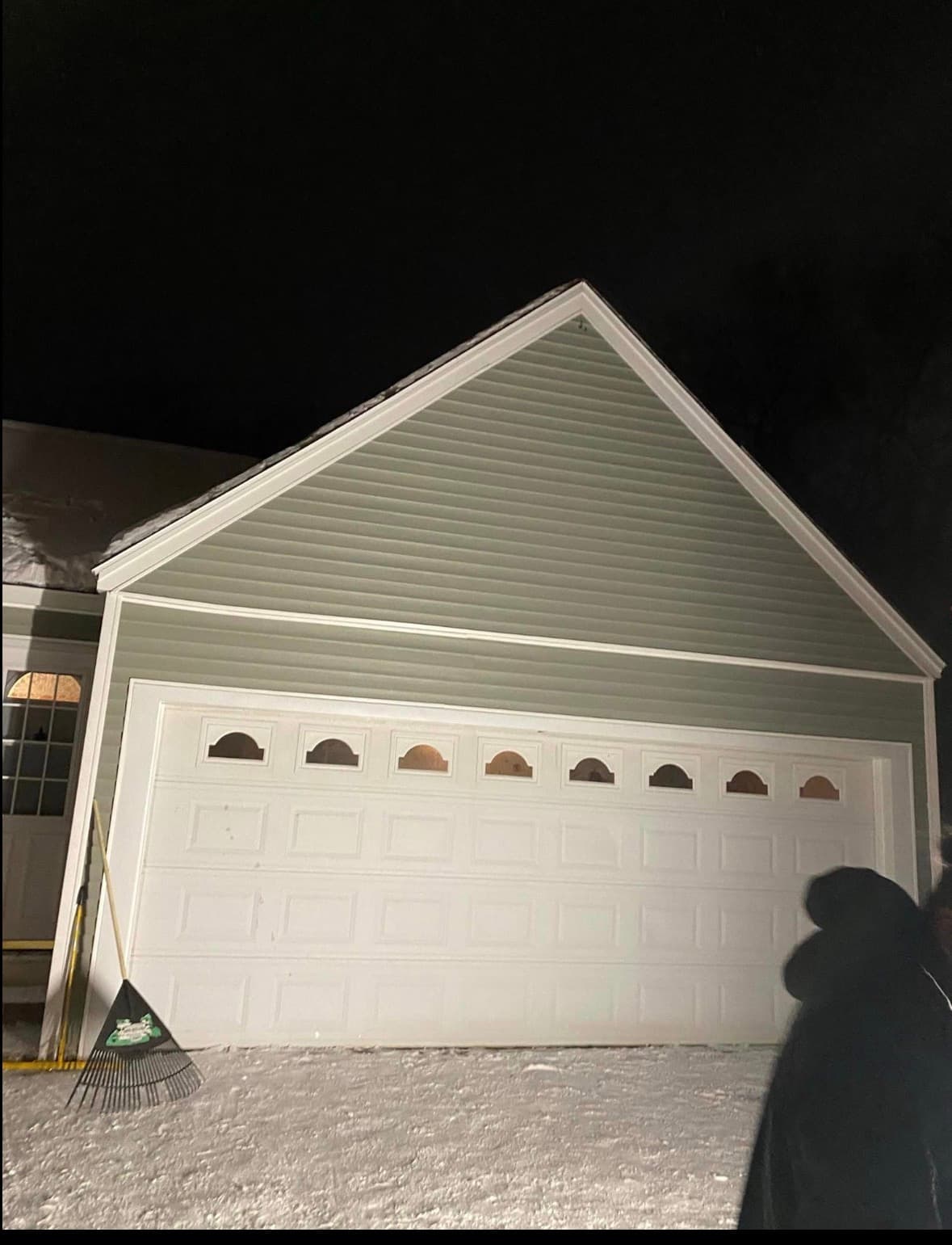 Finished sage-green vinyl siding with white trim on a garage gable