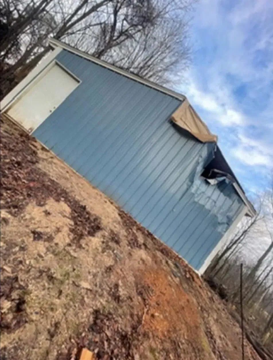 Wind-torn metal siding, tarped to stop the water