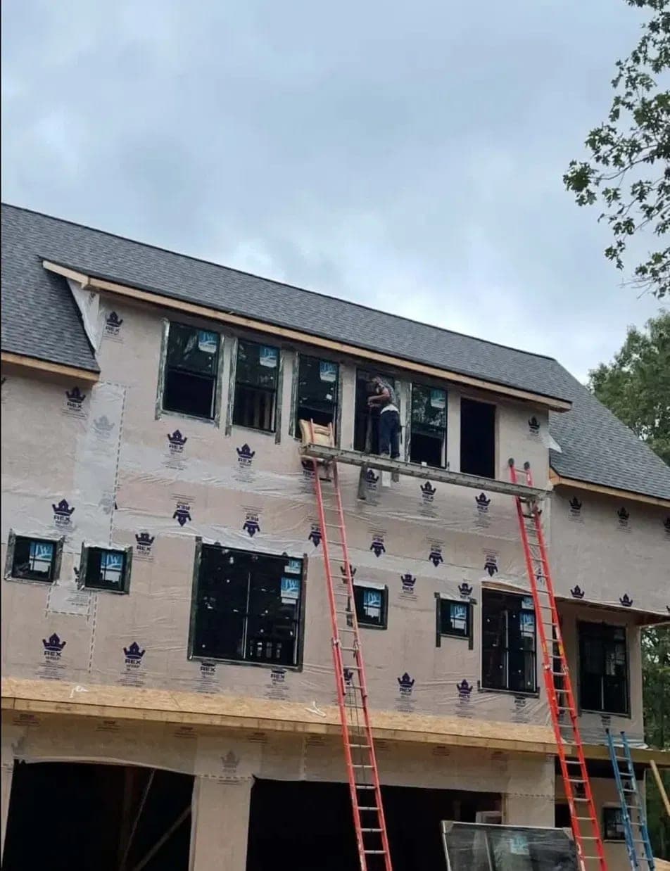 Full window package being installed on a new build with house wrap and ladders